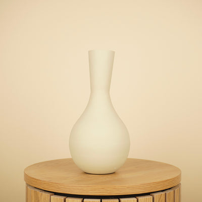 Matte crèmekleurige vaas met ronde buik en lange, smalle hals op een ronde houten tafel.