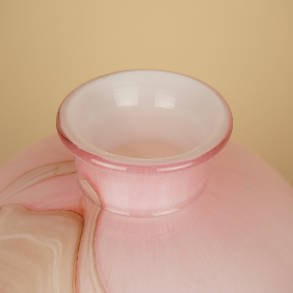 Detail van de uitlopende roze rand en lichte binnenzijde van een ronde vaas met marmerlook.