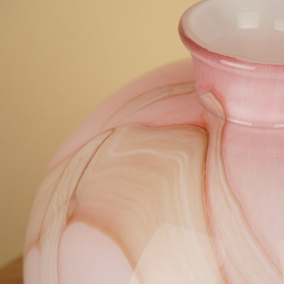 Detail van het golvende marmerpatroon in roze, crème en beige op de glanzende vaas.